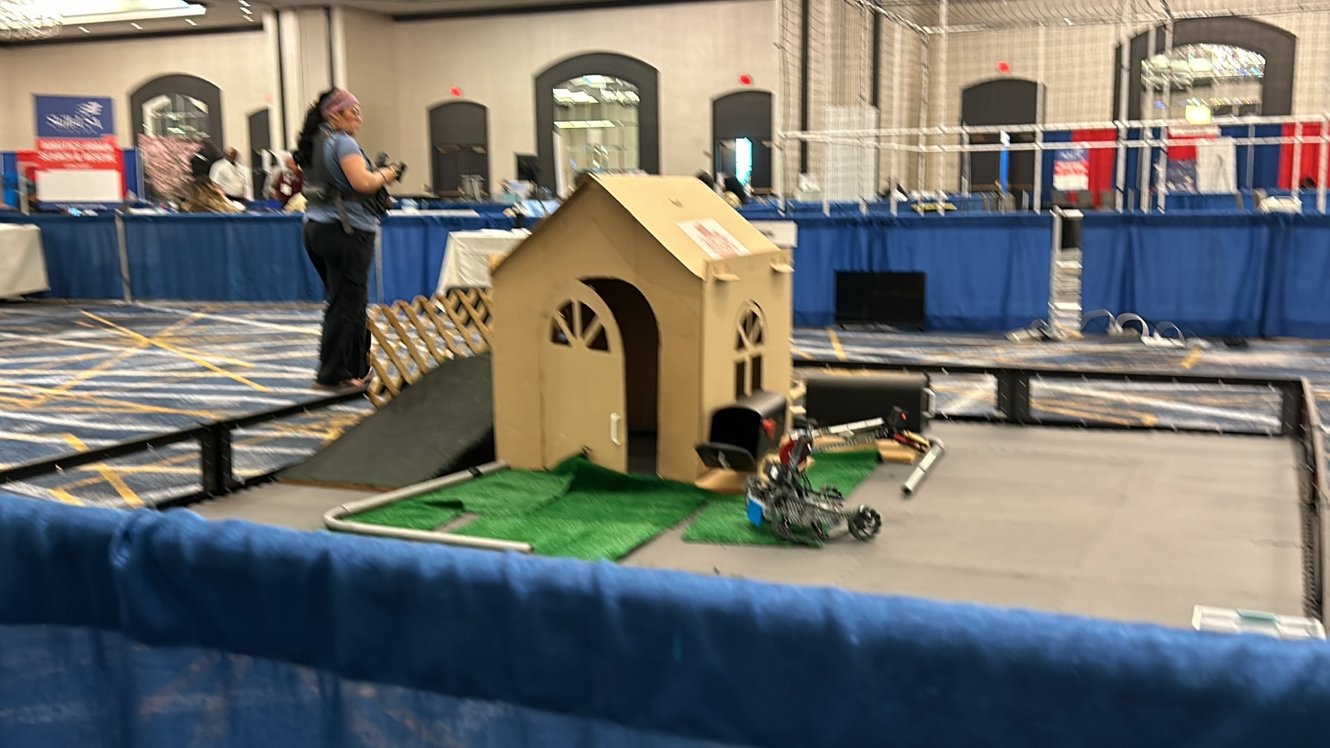 A person standing next to a cardboard dog houseDescription automatically generated